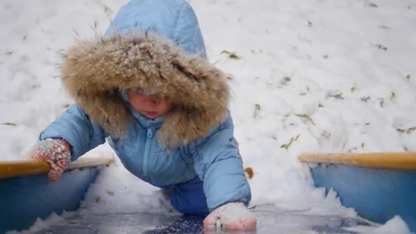 Un bambino piccolo e felice gioca sul parco giochi in inverno — Video Stock
