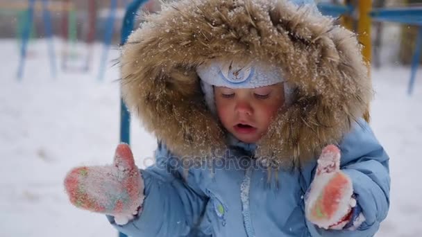 Ein kleines glückliches Kind spielt mit Schneeflocken im Park — Stockvideo