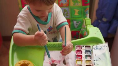 mutlu bir çocuğun bir fırça ile kağıt üzerinde çizer.