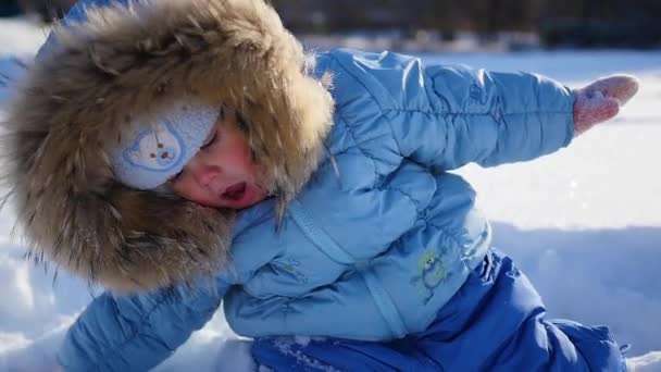 Un pequeño niño feliz juega con copos de nieve en el parque — Vídeos de Stock