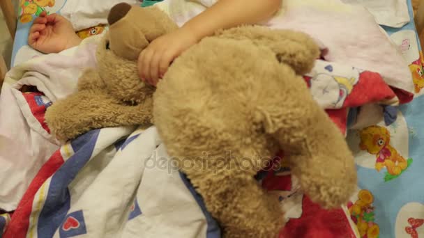 The sweet baby sleeps in a cot with a teddy bear — Stock Video