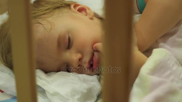 The sweet baby sleeps in a cot and flinches in her sleep — Stock Video