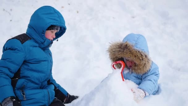 En glad barn leker med snön i parken. begravd i snön — Stockvideo