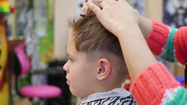 Corte de cabelo de uma criança com tesoura na barbearia — Vídeo de Stock
