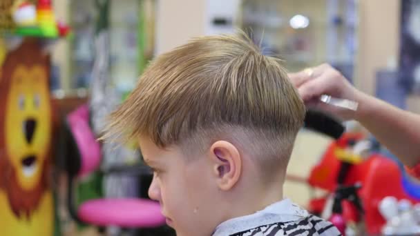 Coupe de cheveux d'un enfant avec des ciseaux dans le salon de coiffure — Video