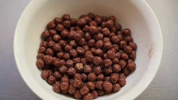 Leche de chorro que cae lentamente en un tazón con bolas de maíz con sabor a chocolate. Moción lenta — Vídeos de Stock