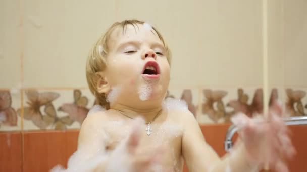 Niño se divierte jugando con burbujas de espuma y jabón en el baño — Vídeos de Stock