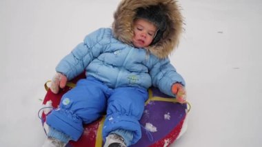 mutlu bir çocuk snowtube içinde karlı bir tepe üzerinde sürmek.