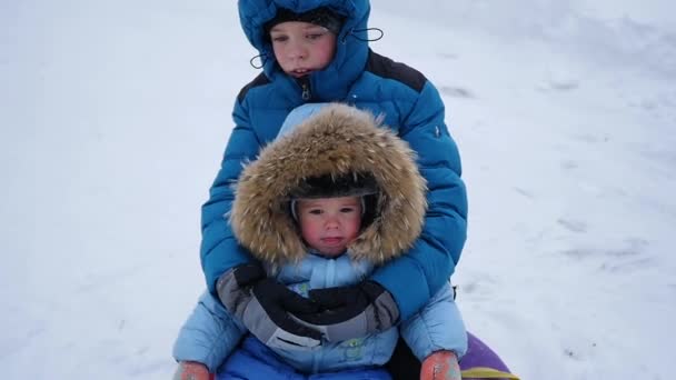 En glad barn rider och leende i snowtube på en snöig backe — Stockvideo