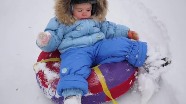 Un enfant heureux monte en snowtube sur une neige — Video