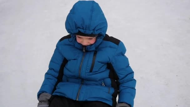 Un niño feliz cabalga y cae en tubo de nieve en una colina nevada — Vídeos de Stock