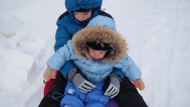 Un bambino felice cavalca e sorride in snowtube su una collina innevata — Video Stock