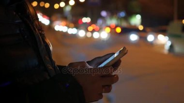 Adam sms manifatura app Smartphone'da gece şehirde, kış saati kullanarak.