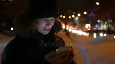 Adam sms manifatura app Smartphone'da gece şehirde, kış saati kullanarak.