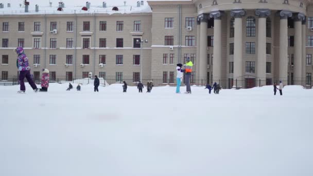 НОВОСИБИРСК, РОССИЯ - 27 НОЯБРЯ: Люди катаются на открытом конькобежном ринге в пасмурный зимний день — стоковое видео