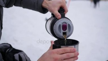 adam açık havada bir termos sıcak çay dökülen. Kış saati