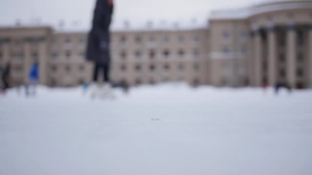 Les gens patinent sur l'anneau ouvert de patinage par une journée nuageuse en hiver dans flou — Video