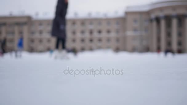 Menschen laufen an einem bewölkten Tag im Winter in Unschärfe auf dem offenen Eislaufring
