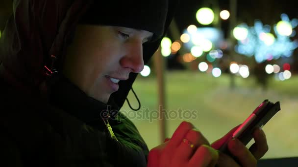 Homem sms mensagens de texto usando aplicativo no smartphone à noite na cidade, tempo de inverno. close-up — Vídeo de Stock