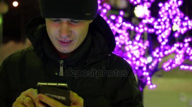 Adam sms manifatura app Smartphone'da gece şehirde, kış saati kullanarak. portre