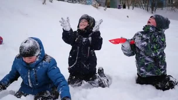 Glada barn som leker i snön kasta snö upp i park — Stockvideo