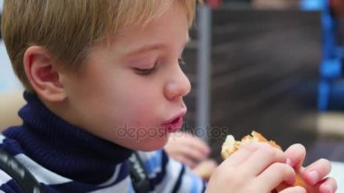 Çocuk bir çörek tavuk ile fast food Restoran yiyor.