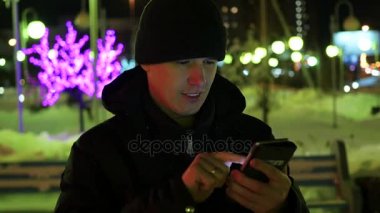 Adam sms manifatura app Smartphone'da gece şehirde, kış saati kullanarak. portre
