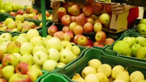 Een werkende man in de supermarkt zet de appels fruit in de schaaltjes — Stockvideo