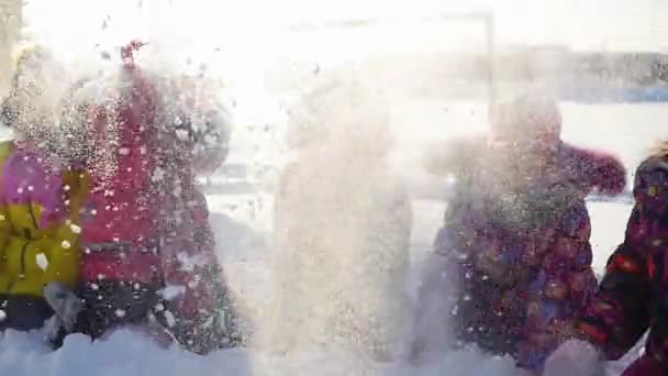 Fröhliche Kinder spielen im Schnee und werfen Schnee in Park — Stockvideo