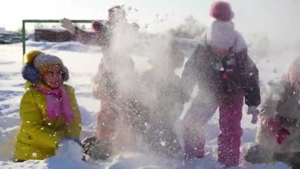 Crianças alegres brincando na neve jogando neve no parque — Vídeo de Stock