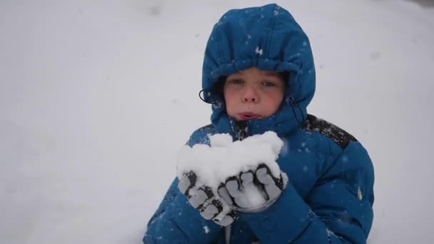 Boy blows snow with hands closeup in slowmo. Snow storm — Stock Video