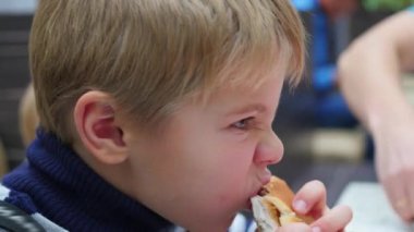 Çocuk bir çörek tavuk ile fast food Restoran yiyor.