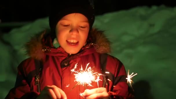 Das Kind hält die Wunderkerzen im Winter draußen. Zeitlupe — Stockvideo
