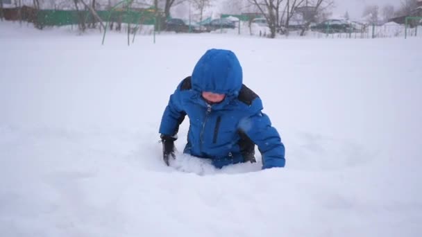 Criança jogando neve sobre si mesmo e gosta no parque de inverno — Vídeo de Stock