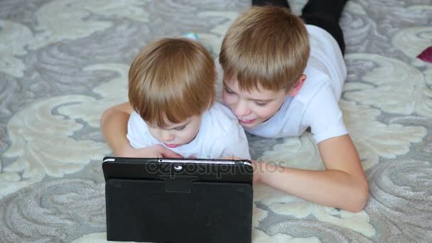 Dzieci wyglądają bajki na komputerze typu tablet na piętrze — Wideo stockowe