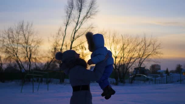 Lány játszik a baba télen napnyugtakor — Stock videók