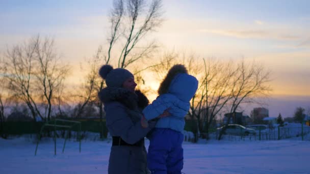 Kız kış zamanında gün batımında bebekle oynuyor — Stok video