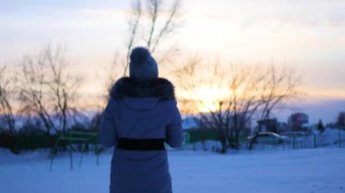 kız kış zamanında gün batımında bebekle oynuyor