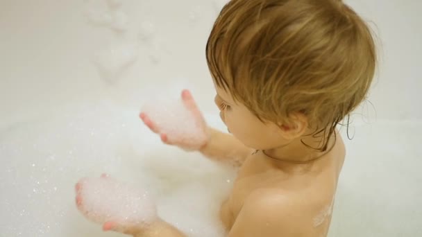 Niño se divierte jugando con espuma en el baño — Vídeo de stock