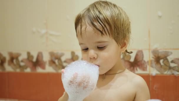 Eğlenceli olan çocuğun köpük banyosu ile oynarken. Avuç içi ile darbeler köpük — Stok video