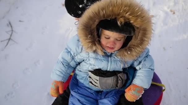 En glad barn rider och leende i snowtube på en snöig backe — Stockvideo