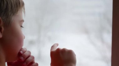 Genç bir parmak pencere camına çizer. Dışında bulanıklık kar