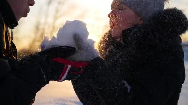 Menina e cara sopra neve com as mãos no pôr do sol fundo — Vídeo de Stock