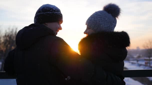 Пара стоїть на мосту і цілується на заході сонця — стокове відео
