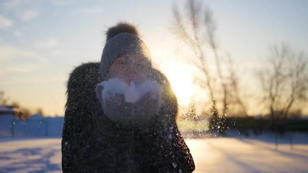 Flicka blåser snö med händerna på sunset bakgrund — Stockvideo