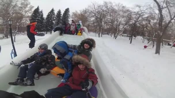 NOVOSIBIRSK, RUSIA - 31 de diciembre de 2016: Los niños se divierten en el deslizamiento de hielo colina abajo durante el día.Selfie — Vídeo de stock