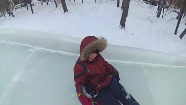 NOVOSIBIRSK, RÚSSIA - 31 de dezembro de 2016: Criança se diverte no deslizamento de gelo descendo a colina no dia.Selfie — Vídeo de Stock