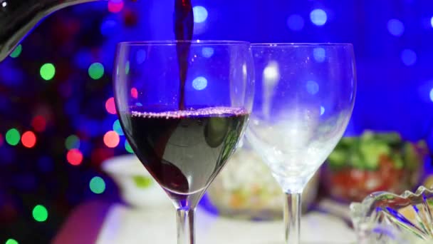 Czerwonego wina przelewa się do szklanki. W tle, bokeh świateł i Girlandy choinkowe Christmas — Wideo stockowe