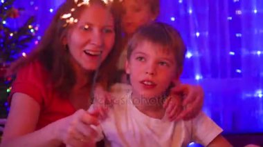 Mutlu aile maytap partide yaktı. Arka plan, bokeh ışıklar ve Noel köknar çelenk