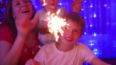 Mutlu aile maytap partide yaktı. Arka plan, bokeh ışıklar ve Noel köknar çelenk